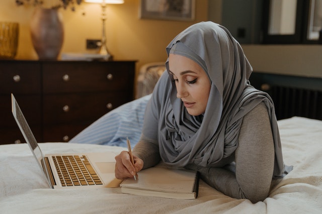 woman writing on bed